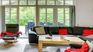 A spacious living room with a large black leather sofa, a wooden coffee table, and a leather armchair.
