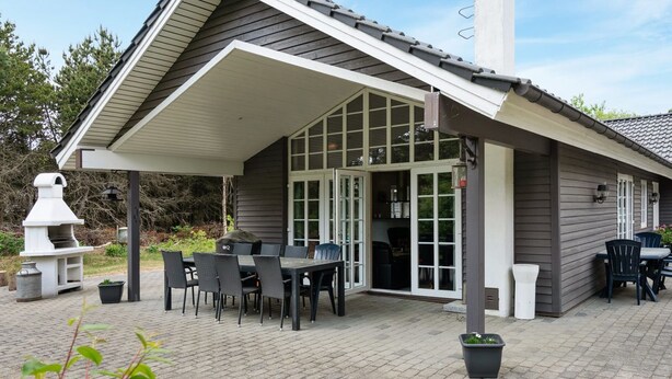 A covered patio area with a dining table and chairs, a grill, and a chimney.