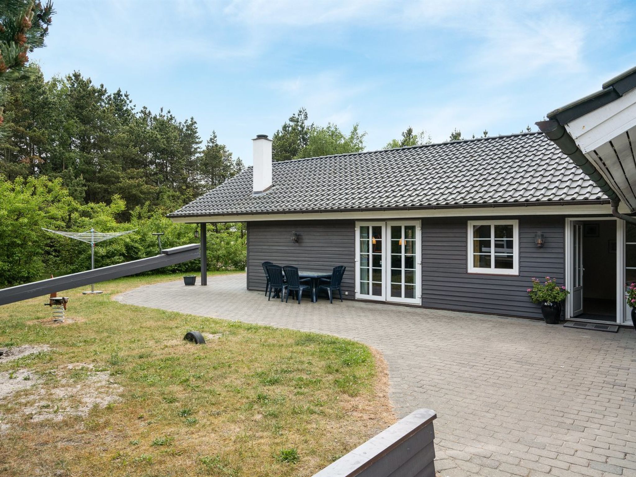 Une maison dotée d’un patio, d’un espace extérieur couvert aménagé en salon et d’une cheminée.