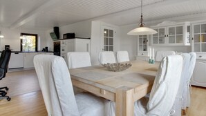 A modern kitchen with white cabinets, a wooden dining table, and chairs. - "Lokke" - 19km from the sea by Interhome (Skærbæk)