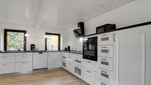 A modern kitchen with white cabinetry, a black oven, and a television mounted above the stove. - "Lokke" - 19km from the sea by Interhome (Skærbæk)