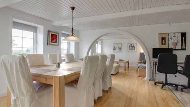 A spacious room with a wooden dining table, white chairs, and a hanging light fixture. - "Lokke" - 19km from the sea by Interhome (Skærbæk)