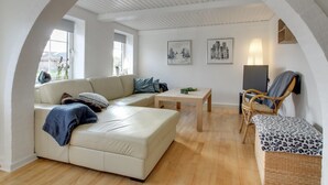 A modern living room with a sofa, a table, and a chair. There are windows and artwork on the walls. - "Lokke" - 19km from the sea by Interhome (Skærbæk)