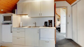 A compact kitchen with white cabinets, a sink, and a coffee maker.