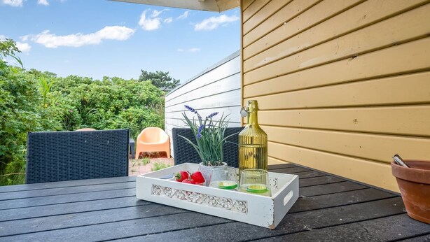 A patio table with a white tray containing a bottle, strawberries, and green leaves. - "Tedora" - 300m from the sea by Interhome (Fanø)