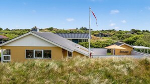 A modern house with a sloped roof, a flagpole, and a grassy foreground. - "Tedora" - 300m from the sea by Interhome (Fanø)