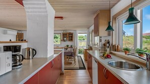 A modern kitchen with red cabinets, a stainless steel sink, and a window overlooking a garden. - "Tedora" - 300m from the sea by Interhome (Fanø)