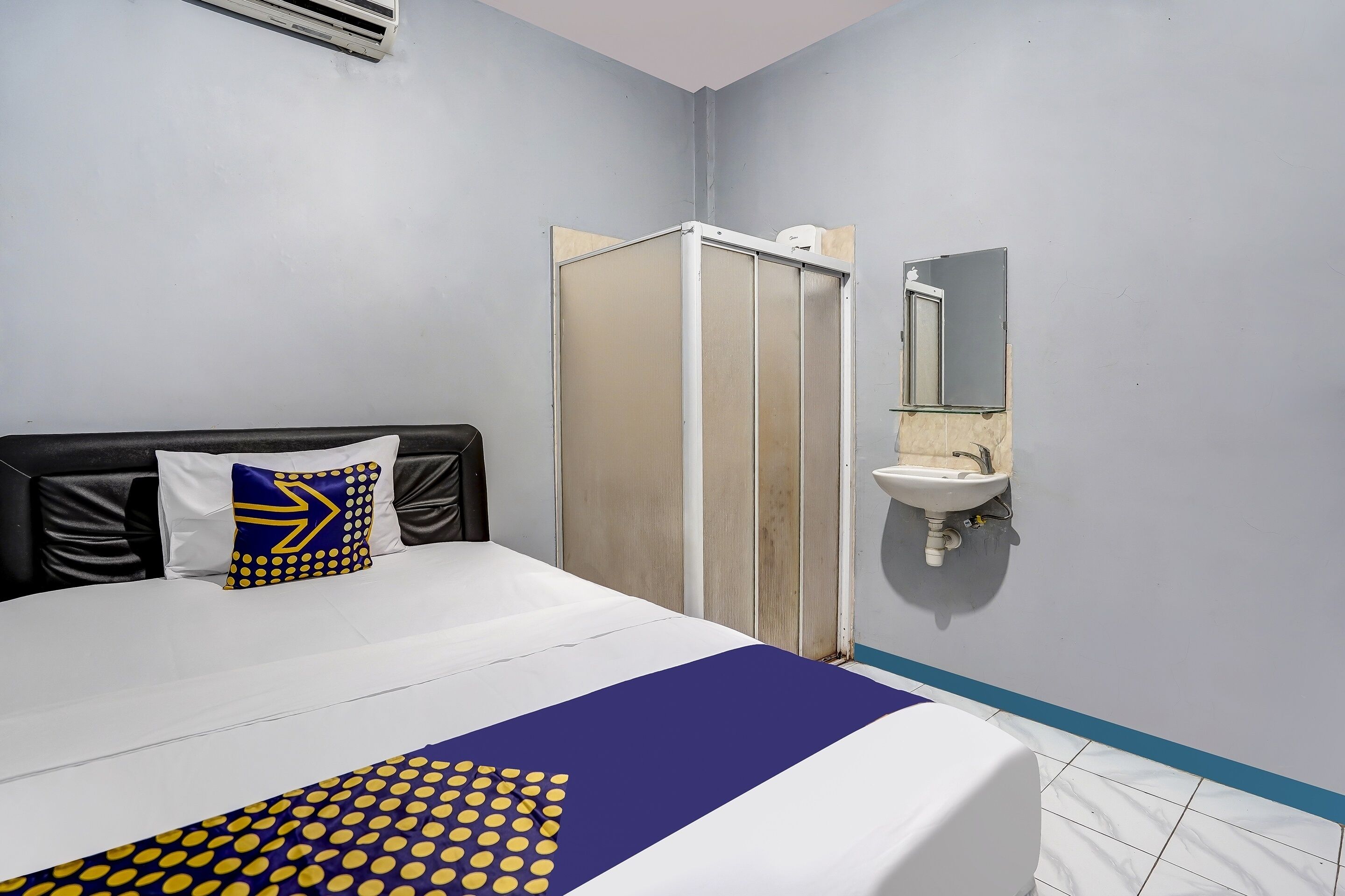 A hotel room with a bed, a bathroom with a shower, and a sink.