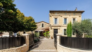 A traditional stone building with a gravel driveway leading to a gated entrance.