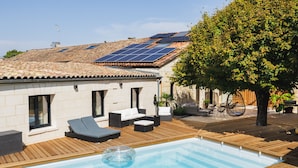 A swimming pool with lounge chairs and a tree.