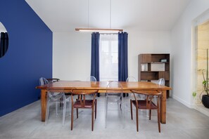 Un comedor moderno con una mesa y sillas de madera, una pared azul y una estantería.