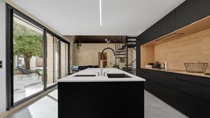 A modern kitchen with a central island, black cabinetry, and a view to the outside.