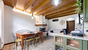 Ein Essbereich mit Holztisch und Stühlen, einem Kamin, einer Couch und einer Küchenzeile mit Schränken.