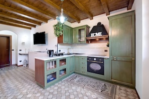 Cocina con gabinetes verdes, estufa negra y piso de baldosas.