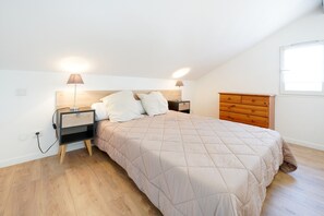 A bedroom with a bed, nightstands, a dresser, and a window.