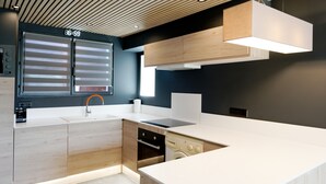 Eine moderne Küche mit Holzausbau, Backofen, Geschirrspüler und einem Fenster mit Jalousien.