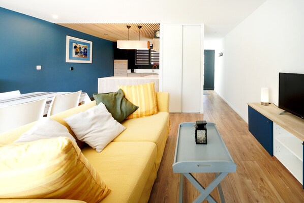 A modern living room with a yellow sofa, a small table, and a television.