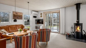 A cozy living room with a sofa, chairs, a TV, and a wood-burning stove. - "Andine" - 1.2km from the sea by Interhome (Fanø)
