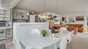 A modern kitchen with white cabinets, a dining area with a striped tablecloth, and a living room with a brown sofa. - "Andine" - 1.2km from the sea by Interhome (Fanø)