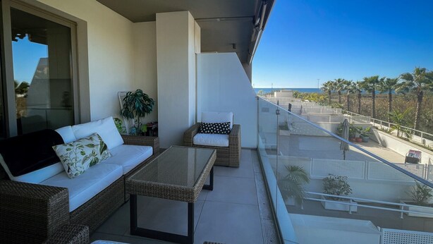 A balcony with wicker furniture, a glass table, and a view of the sea. - Apartment "Sunny Panorama" with Sea View, Shared Pool & Wi-Fi (Torrox)