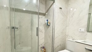 A modern bathroom with a glass-enclosed shower, a white toilet, and a vanity with a mirror. - Apartment "Sunny Panorama" with Sea View, Shared Pool & Wi-Fi (Torrox)