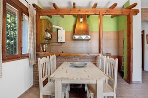 Un coin repas avec une table et des chaises en bois, un luminaire suspendu et un mur en briques agrémenté d’un pare-feu en carreaux.