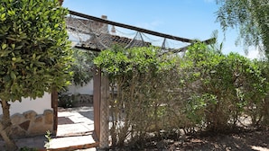 A courtyard with a wooden pergola, stone wall, and a small garden area. - Holiday Home 'Mora' with Private Terrace, Private Garden and Wi-Fi (Vejer de la Frontera)