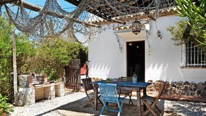 A patio with a table and chairs, a hammock, and a white building with a tiled roof. - Holiday Home 'Mora' with Private Terrace, Private Garden and Wi-Fi (Vejer de la Frontera)