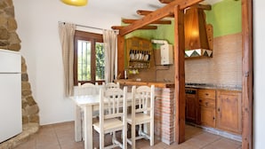 A kitchen with a dining table, chairs, a wooden counter, and a stone wall. - Holiday Home 'Mora' with Private Terrace, Private Garden and Wi-Fi (Vejer de la Frontera)