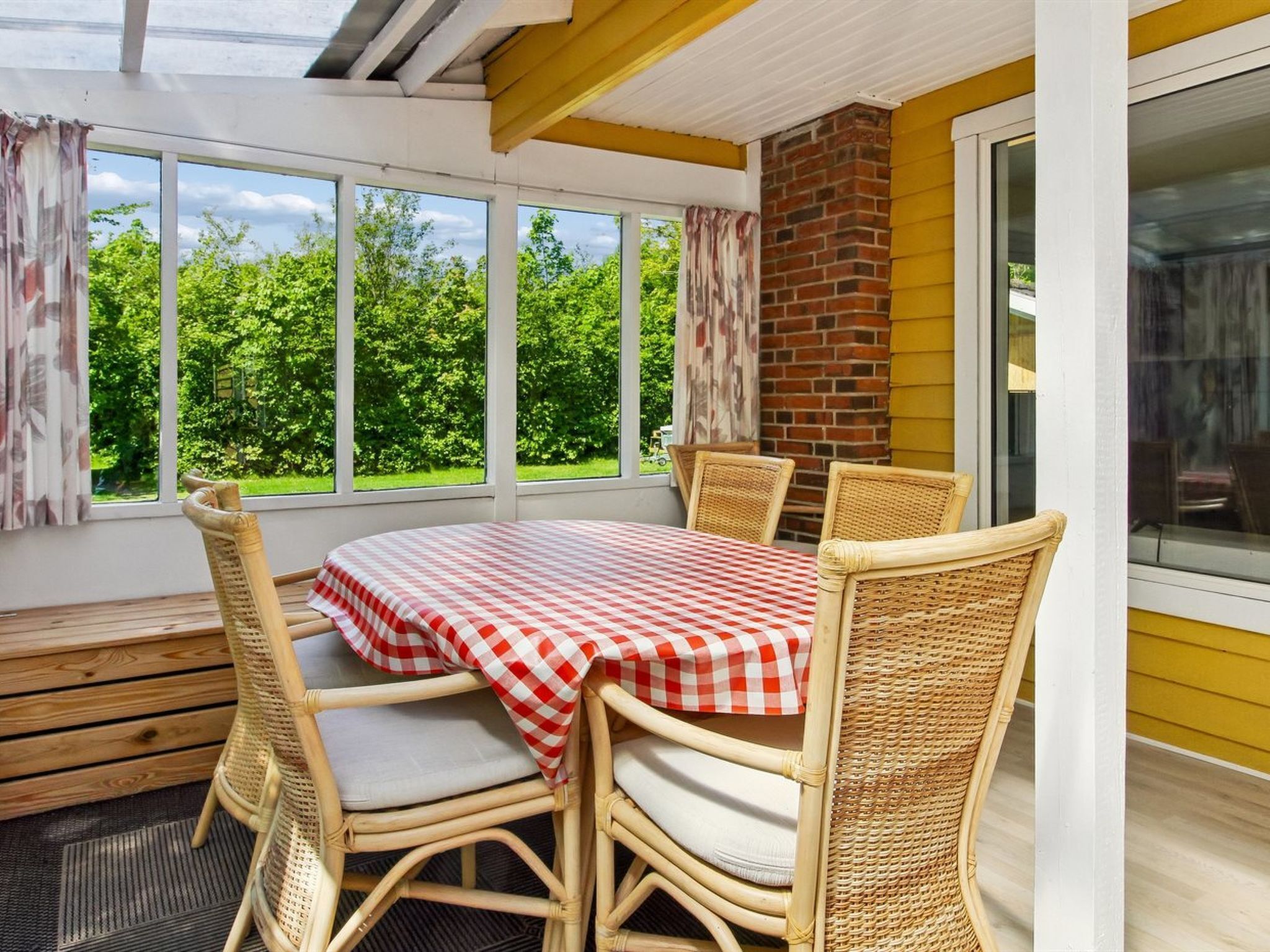 Un coin repas avec une table et des chaises, de grandes fenêtres et un mur en briques.