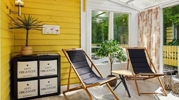 A yellow exterior wall, a black and wooden chair, a small table, and a sign with 'Let's Organize' text.