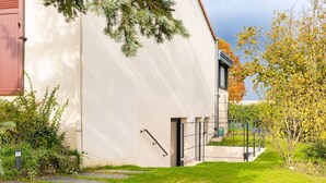 Un edifici modern amb façana blanca, una porta ben visible i una petita zona exterior amb barana metàl·lica.