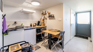 Una cuina compacta amb zona de menjador, un refrigerador petit i un rentaplat.
