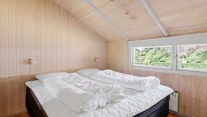 Et soveværelse med seng, trævægge, et vindue med udsigt og en loftlampe.