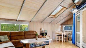 Et interiør i træ med en sofa, et bord og et spiseområde.