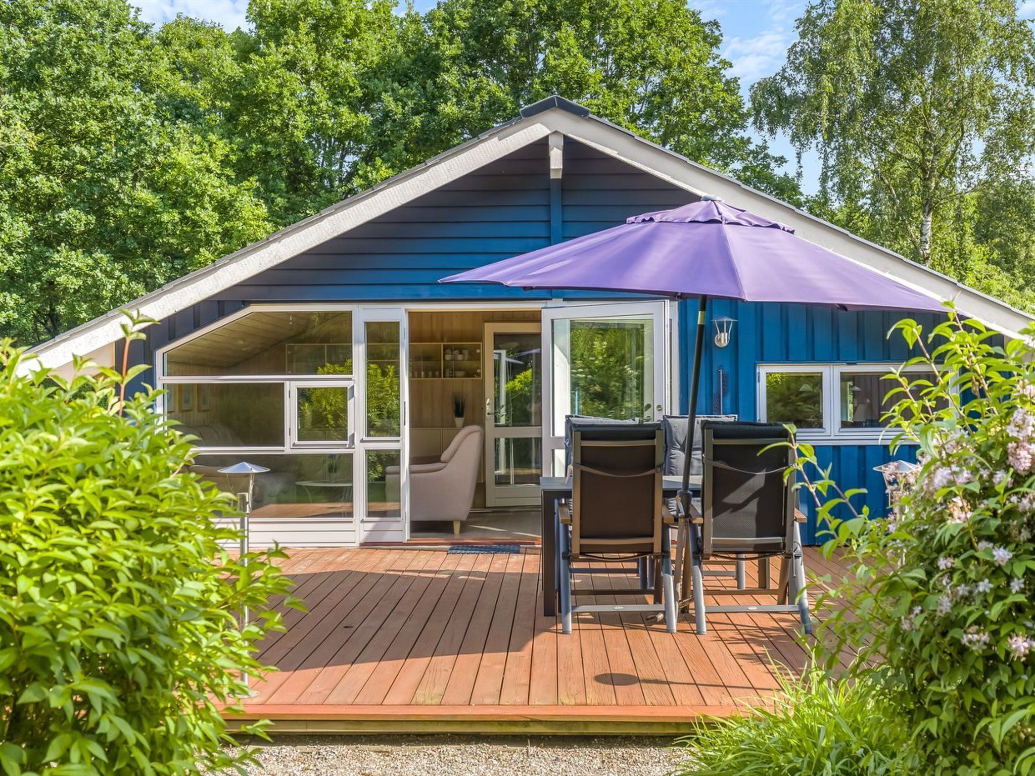 Una casa azul con una terraza, una sombrilla y una silla.