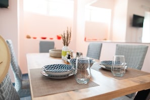 A dining table with plates, glasses, and a vase with dried plants. - Kos Dream Beachwalk Apartment with Private Terrace, Balcony, and Wi-Fi (???)