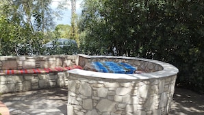 A stone fire pit with a bench and a colorful blanket. - Kos Dream Beachwalk Apartment with Private Terrace, Balcony, and Wi-Fi (???)
