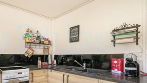 Una cocina con estufa, cafetera y un estante en la pared.