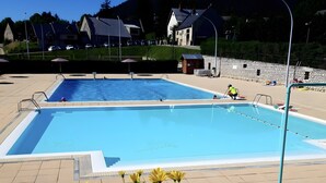 Una piscina con borde empedrado, rodeada por una valla, y una montaña al fondo.