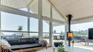 Una habitación amplia con un ventanal grande, un sofá, una mesa con objetos decorativos y una chimenea.