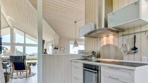 Una cocina moderna con armarios blancos, una campana extractora de acero inoxidable y un amplio ventanal con vistas panorámicas.
