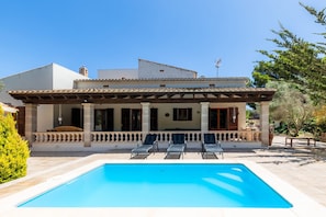 A two-story house with a swimming pool, outdoor seating, and a covered patio.