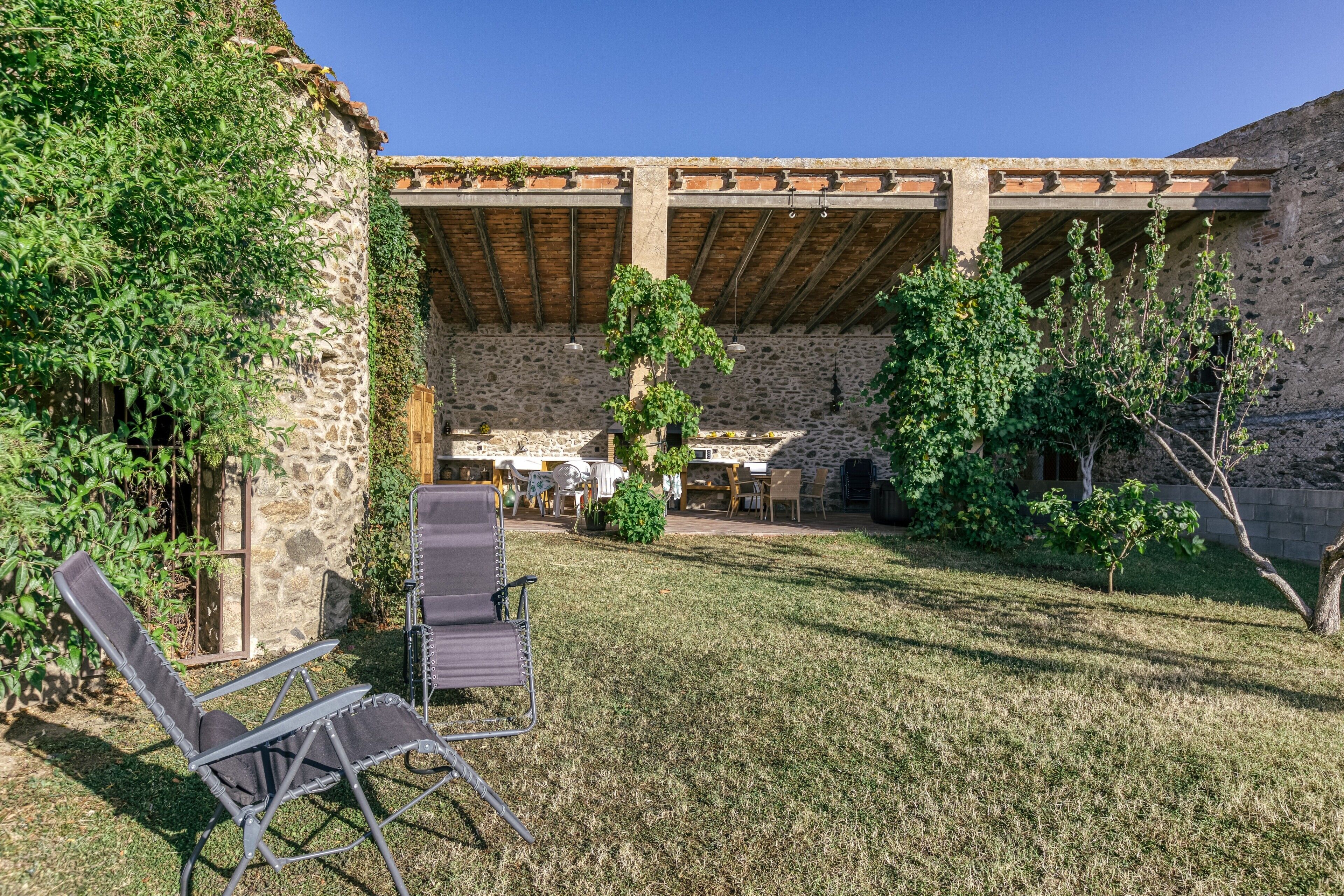 A courtyard with stone walls, a covered seating area, and outdoor furniture.