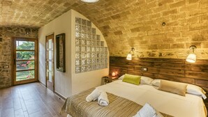 Un dormitorio con una cama grande, cabecera de madera, mesita de noche y ventana con vista a zonas verdes.