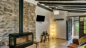 Una pared de piedra, una chimenea, un televisor, un sofá y una puerta que da al exterior.