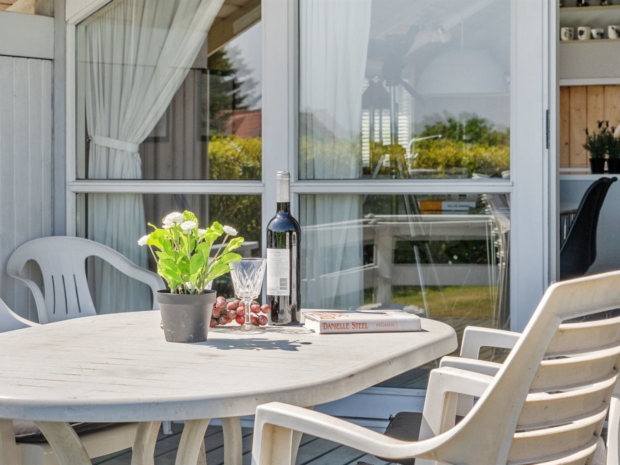 Een ronde tafel met een bloempot, een fles en een boek.