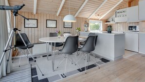 Une cuisine moderne avec des meubles blancs, un îlot central et un coin repas comprenant une table ronde et quatre chaises.