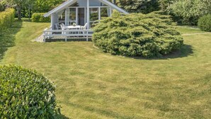 Une maison moderne dotée d’un patio couvert et d’une pelouse bien entretenue.