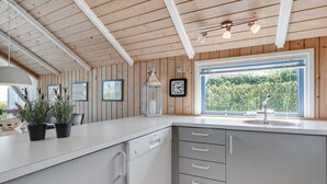 Une cuisine moderne avec un lambris en bois, une grande fenêtre et un évier.